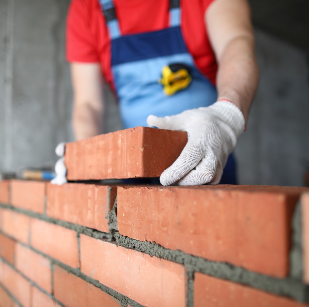 Un homme debout construisant un mur avec des briques