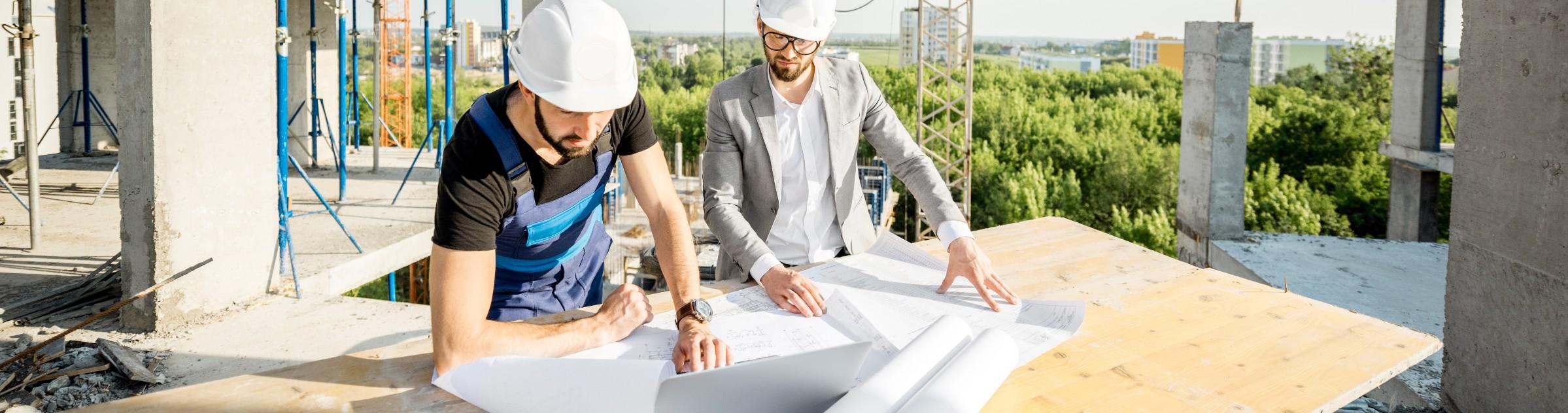 Deux hommes de chantier avec un casque lisant un plan